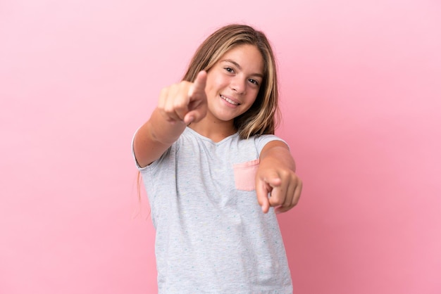 Kaukasisch meisje geïsoleerd op een roze achtergrond die naar voren wijst met een gelukkige uitdrukking