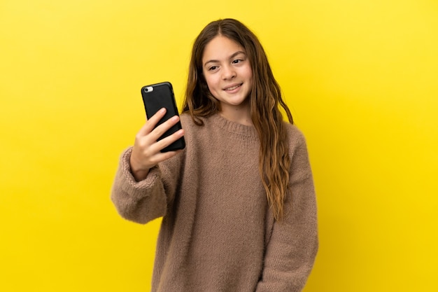 Kaukasisch meisje geïsoleerd op gele achtergrond die een selfie maakt