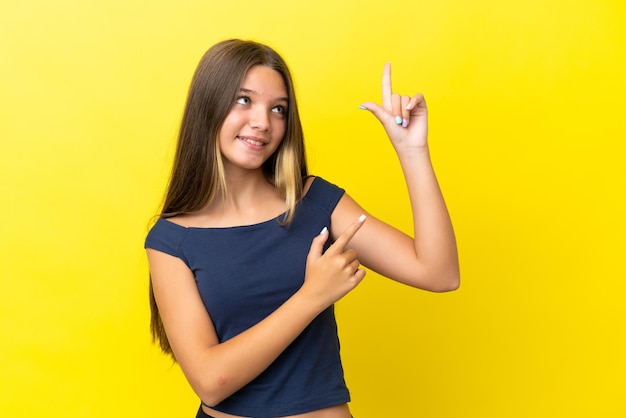 Kaukasisch meisje geïsoleerd op gele achtergrond wijzend met de wijsvinger een geweldig idee