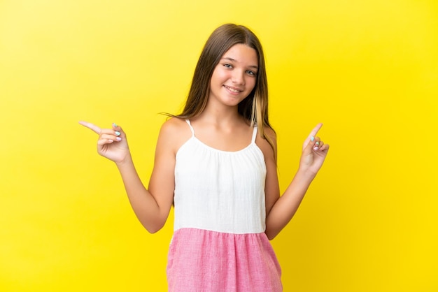 Kaukasisch meisje geïsoleerd op gele achtergrond wijzende vinger naar de laterals en happy