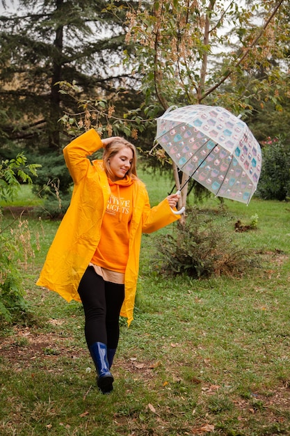 Kaukasisch meisje in een gele regenjas die buiten loopt op de regenachtige dag in de herfst Mensen in de herfst