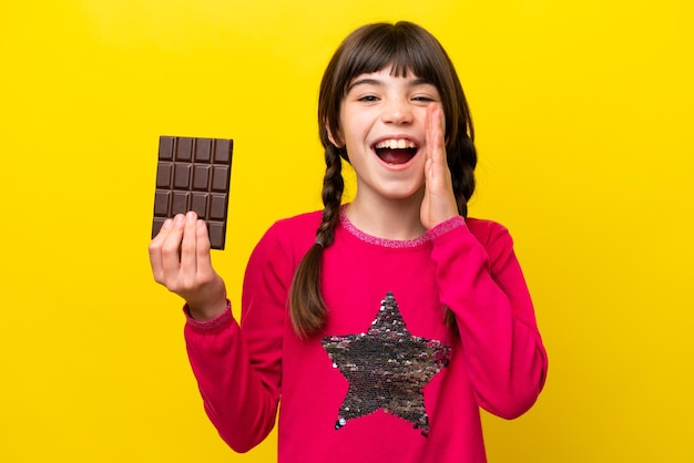 Kaukasisch meisje met chocolade geïsoleerd op gele achtergrond met verrassing en geschokte gezichtsuitdrukking