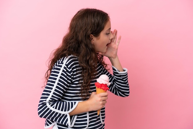 Kaukasisch meisje met een ijsje geïsoleerd op een roze achtergrond schreeuwend met de mond wijd open naar de zijkant