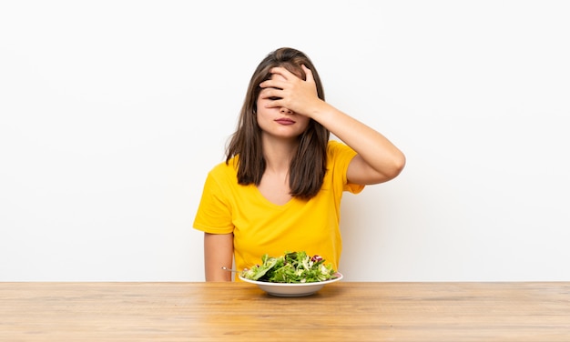 Kaukasisch meisje met salade die ogen behandelen door handen