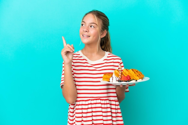 Kaukasisch meisje met wafels geïsoleerd op een blauwe achtergrond die een geweldig idee benadrukt