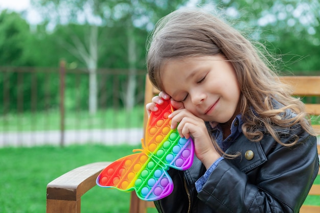 Foto kaukasisch meisje speelt met pop it siliconen trendy regenboogcolow-speelgoed