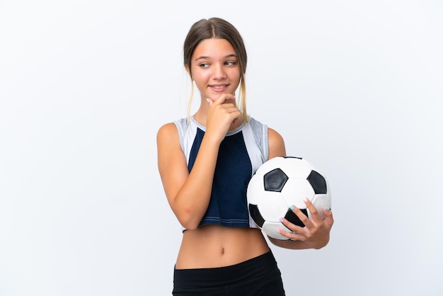 Kaukasisch meisje voetballen geïsoleerd op een witte achtergrond op zoek naar de kant en glimlachen