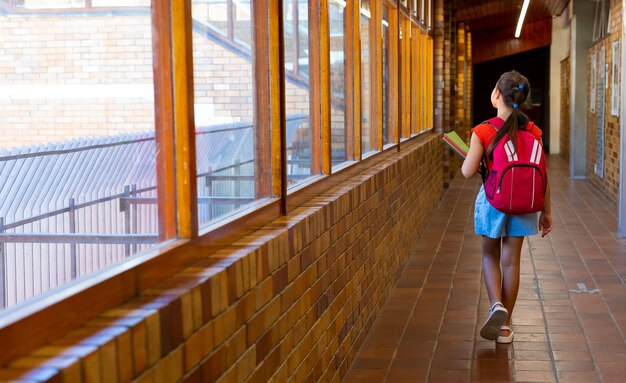 Foto kaukasisch schoolmeisje loopt met schooltas en boeken op de schoolcorridor kopieerruimte