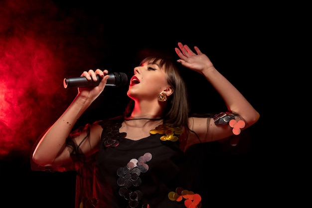 Kaukasisch zangeresportret dat op donkere studioachtergrond in neonlicht wordt geïsoleerd