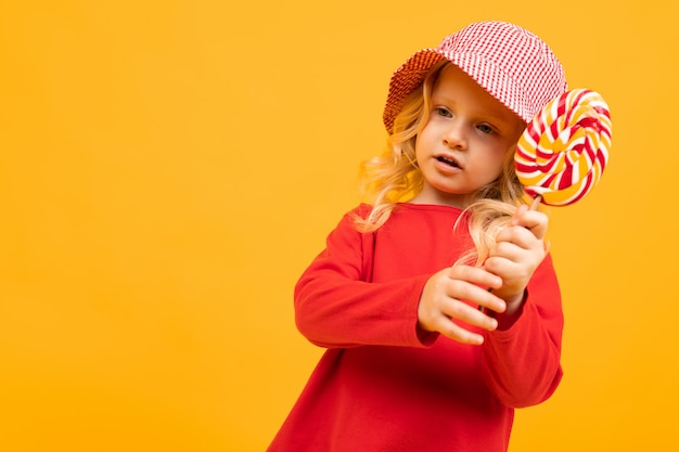 Kaukasische aantrekkelijke baby met een ronde lolly op een gele muur