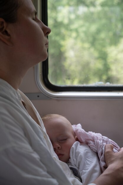 Kaukasische baby slaapt reizend met de trein op moederschoot