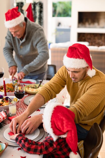 Kaukasische familie van meerdere generaties met kerstmutsen met kerstmaaltijd. familie kersttijd en feest samen thuis.