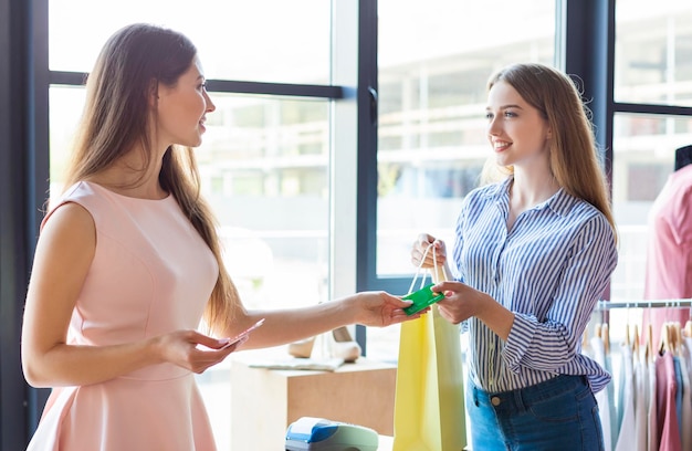 Kaukasische jonge dame betalen met creditcard voor aankoop bij Boutique