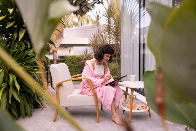 Foto kaukasische jonge designer vrouw brunette maakt schetsen met stylus op het scherm van digitale tablet zittend in de achtertuin technologie en mensen concept