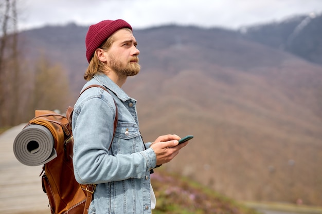 Kaukasische knappe brutale bebaarde man die in de wilde natuur reist met smartphone