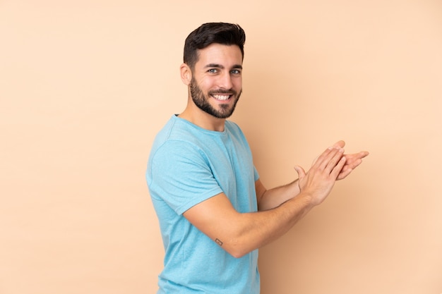 Kaukasische knappe mens bij het beige muur toejuichen