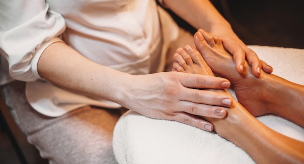 Foto kaukasische masseur die een beenmassagesessie heeft met de cliënt die op de bank ligt