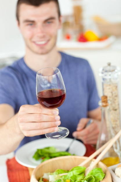 Kaukasische mens die een gezonde salade met wat wijn eet