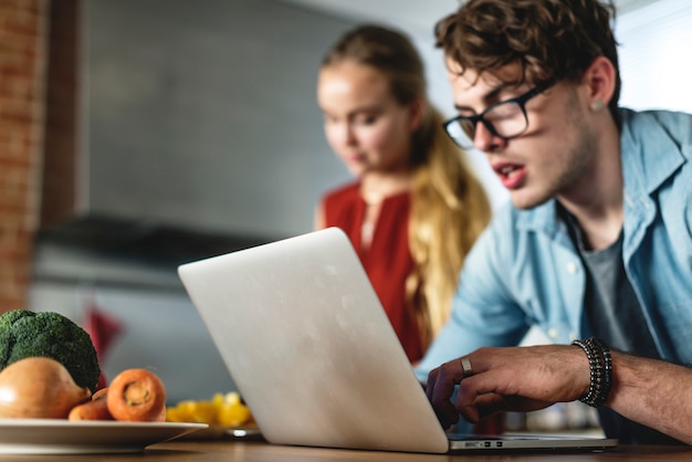 Kaukasische mens die laptop in de keuken met behulp van