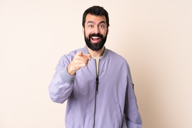 Kaukasische mens met baard die een jasje over geïsoleerd verrast draagt en voorzijde richt