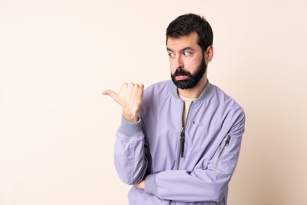 Kaukasische mens met baard die een jasje over ongelukkige muur draagt en aan de kant richt