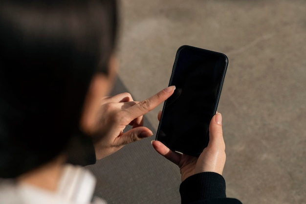 Kaukasische millennial dame in koptelefoon typen op smartphone met leeg scherm buiten close-up