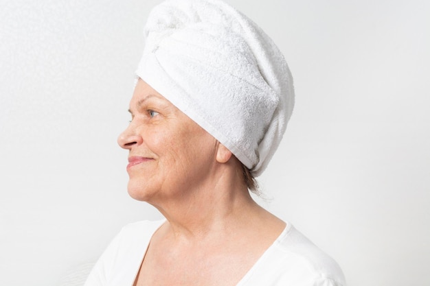 Kaukasische senior vrouw met rimpels met witte handdoek op het hoofd