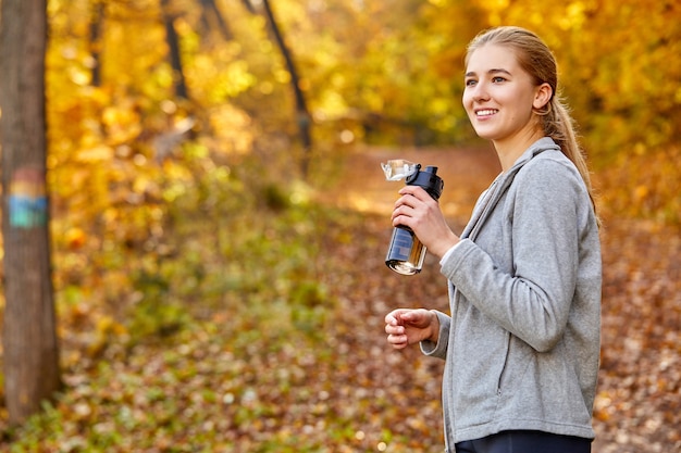 Kaukasische sportieve vrouw met fles water buitenshuis