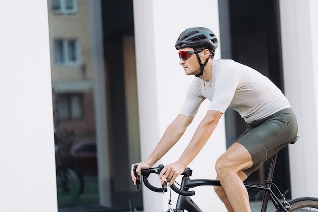 Kaukasische sportman die zwarte fiets gebruikt om in de frisse lucht te fietsen Gezonde man met sportkleding, helm en bril Actief levensstijlconcept