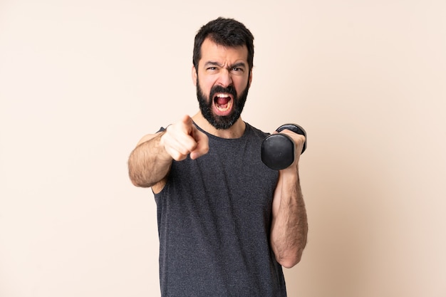 Kaukasische sportmens met baard die gewichtheffen over geïsoleerde muur gefrustreerd maken en naar voren wijzen