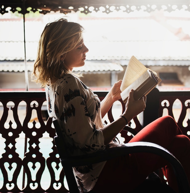 Kaukasische vrouw die het boek leest bij het balkon