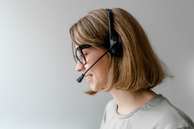 Kaukasische vrouw die met hoofdtelefoon werkt die bedrijfsoproepen beantwoordt als geïsoleerde copyspace van de technische ondersteuningsverzender