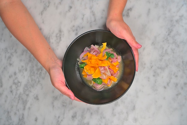 Kaukasische vrouw handen met een heerlijke ceviche plaat op witte tafel achtergrond