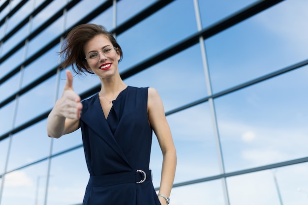 Kaukasische vrouw in bureaukleren die telefonisch dichtbij het bureaugebouw spreken