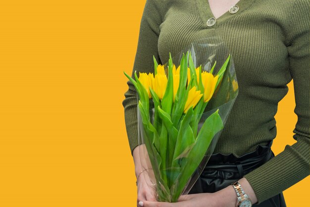 Kaukasische vrouw in het groene boeket van de blouseholding van gele tulpen. Cadeau voor vakantie.