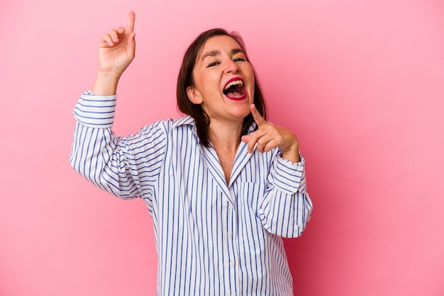 Kaukasische vrouw van middelbare leeftijd geïsoleerd op roze achtergrond dansen en plezier maken.