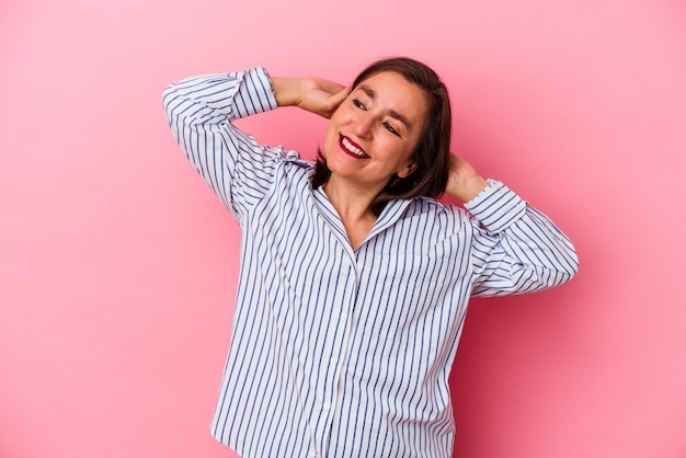 Kaukasische vrouw van middelbare leeftijd geïsoleerd op roze achtergrond zelfverzekerd gevoel, met handen achter het hoofd.