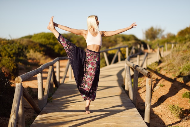 Kaukasische vrouwelijke beoefenen van yoga op houten brug.