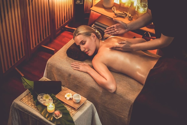 Kaukasische vrouwelijke klant die geniet van ontspannende antistress spa massage en verwennen met schoonheid huid recreatie vrije tijd in warme kaarsverlichting ambient salon spa in luxe resort of hotel Quiescent.