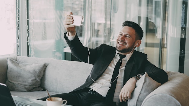 Kaukasische zakenman in formele kleding met online videogesprek met smartphone in café tijdens de lunch