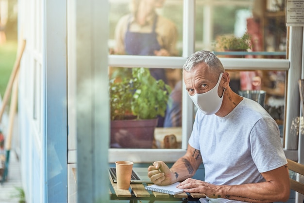 Kaukasische zakenman van middelbare leeftijd met masker die naar de camera kijkt