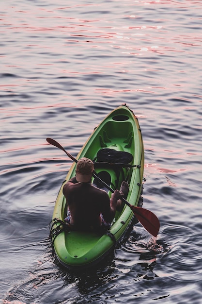 kayaker man peddelkajak bij zonsondergang op zee. Kajakken, kanoën, peddelen