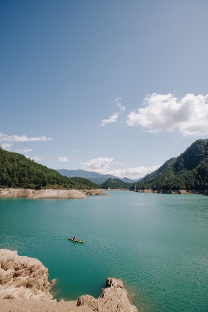 여름에 산으로 둘러싸인 푸른 물 호수에서 맑은 날에 카약 장면