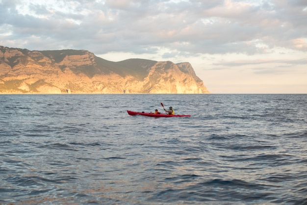 カヤック。山のある島の近くの海でカヌー。海でカヤックをする人。