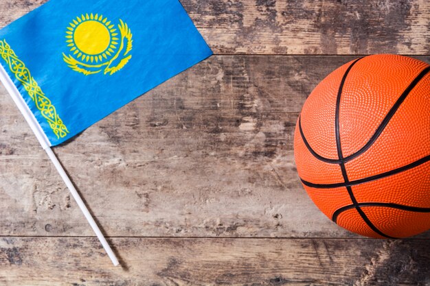 Kazakh flag and basketball on wooden table.