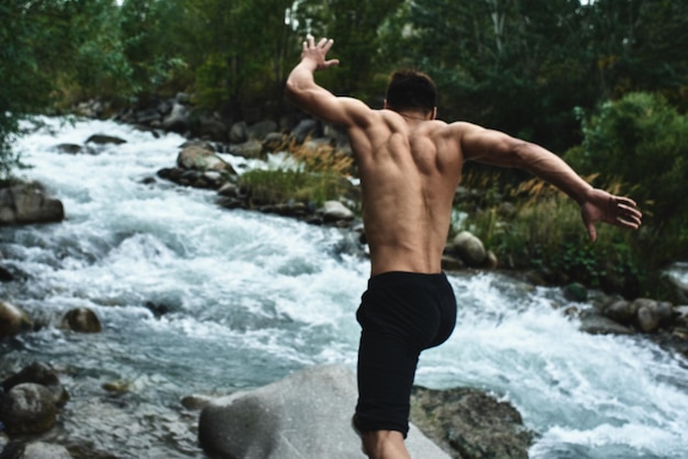 Kazakh muscular athlete man trains and exercises by the river in nature. Asian handsome does extreme fitness workout outdoors