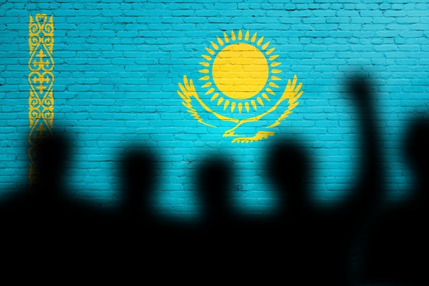 Photo kazakhstan flag painted on a brick wall with people shadows