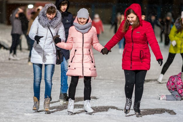 KAZAN RUSSIA 22 JANUARY 2017 Three girls holding hands on skating rink in the evening