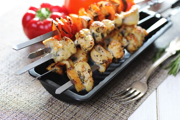 Kebab cooked on metal skewers with vegetables served on white table