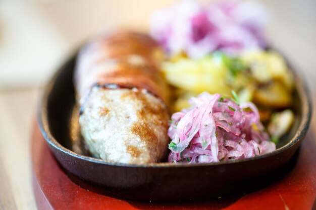 Foto kebab gewikkeld in spek met rode ui in een koekenpan